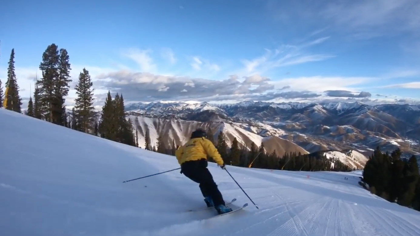 skier in yellow jacket heading down hill